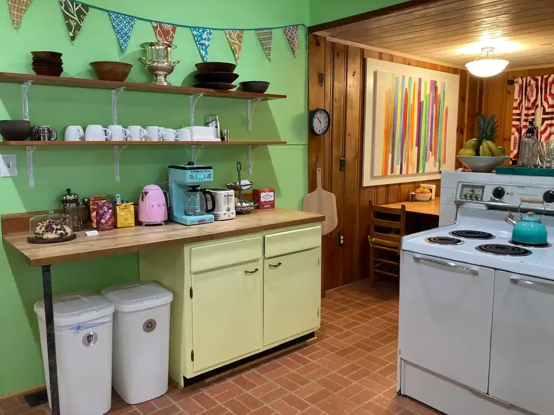 Coffee and tea station, breakfast nook, vintage stove, and kitchen loaded with fresh herbs, bread, and many other food items. 